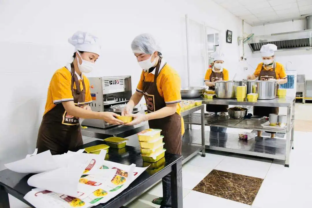 Nhân viên Bếp Dì Năm đang sử dụng giải pháp khay nhôm và máy ép seal từ LEO